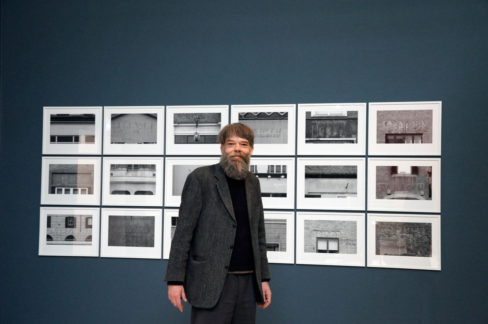 Lasse Krog Møllers museum for oversete ting</br>Lasse Krog Møller foran sine fotografier af skilte, som ikke er der mere. </br>Foto: Kulturmagasinet Fine Spind